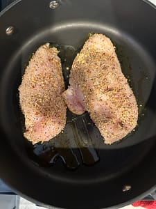 Chicken breast in hot olive oil pan