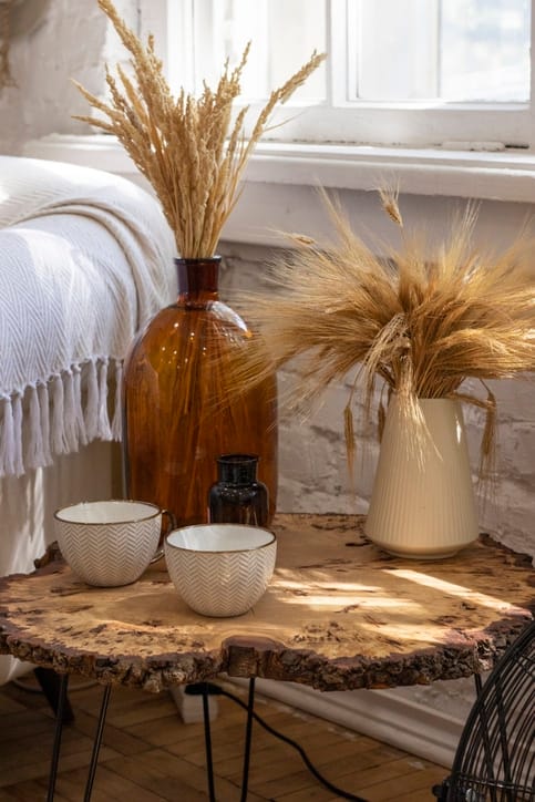 intage interior of a country house with rustic wooden table, white vases, dried flowers and two cups